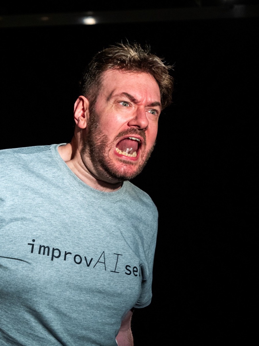 ImprovAIsed — a performer mid-scene in an improvAIsed T-shirt