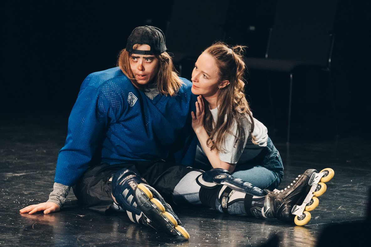 Two ImprovAIsed performers in a physical comedy scene with rollerblades