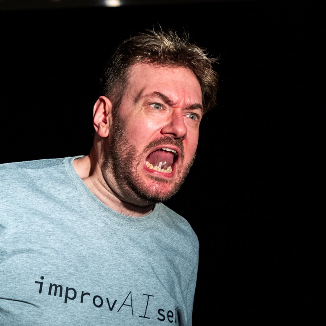 Tom Gilder performing ImprovAIsed against a dark background