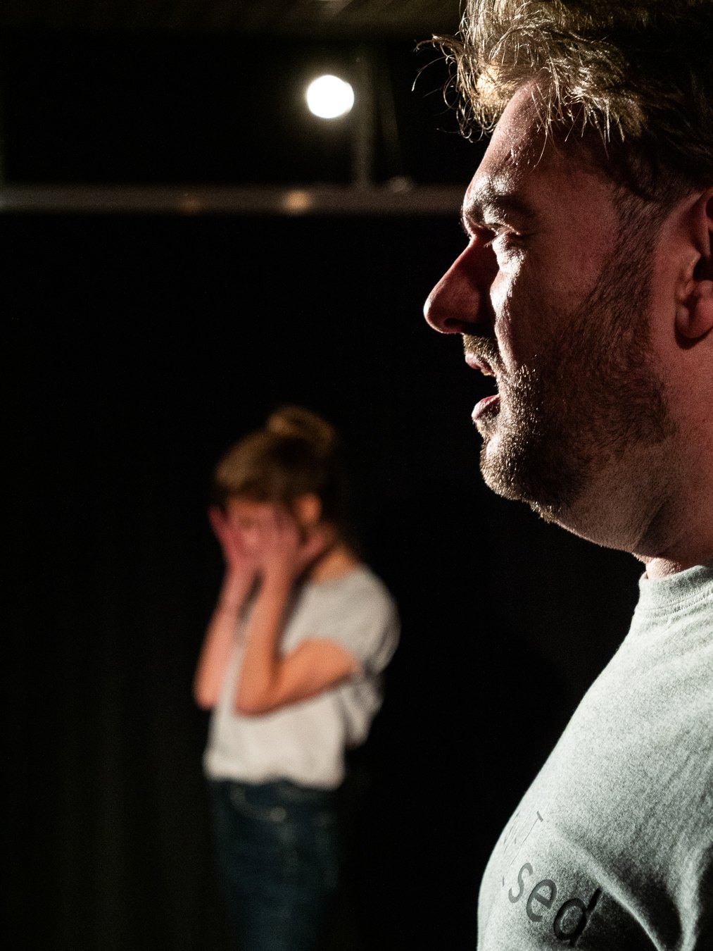 Tom Gilder in profile with Emily Matthews in the background during ImprovAIsed