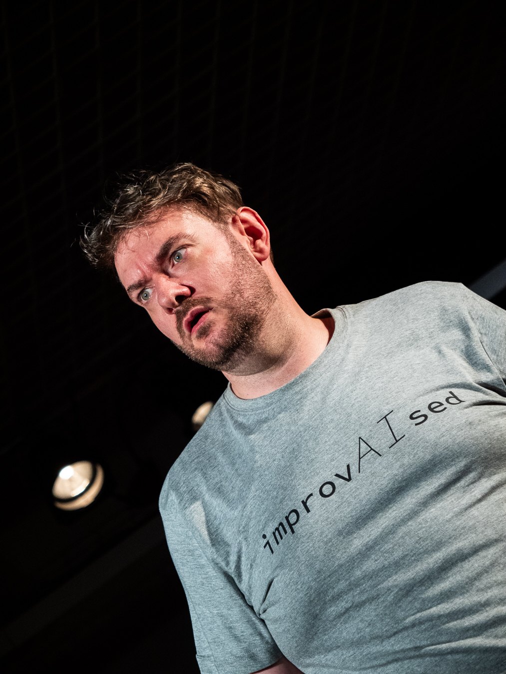 Tom Gilder in a close-up stage photo from ImprovAIsed